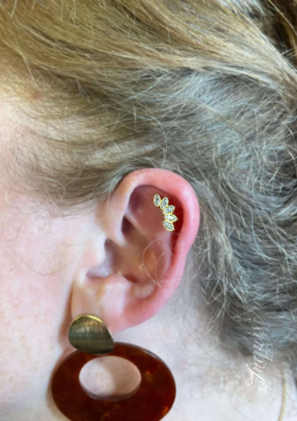 Flat piercing met een gebogen gouden juweel met vijf marquise-steentjes