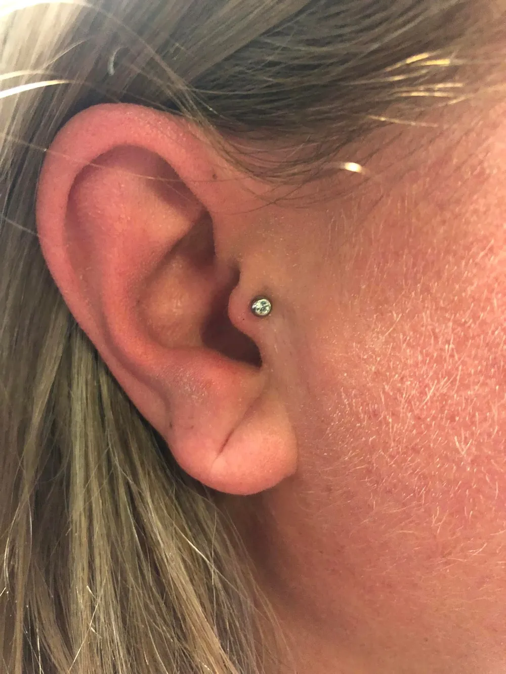 Tragus piercing met een klein zilverkleurig steentje
